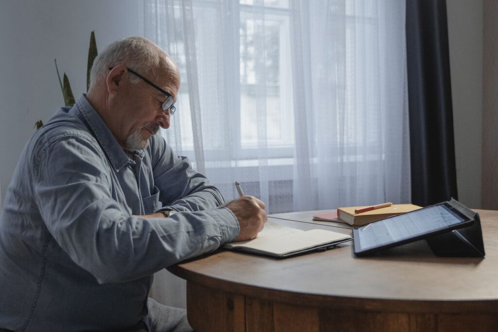 elderly person writing on a notebook