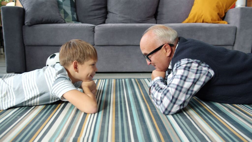 grandfather and grandson lying on a striped carpet