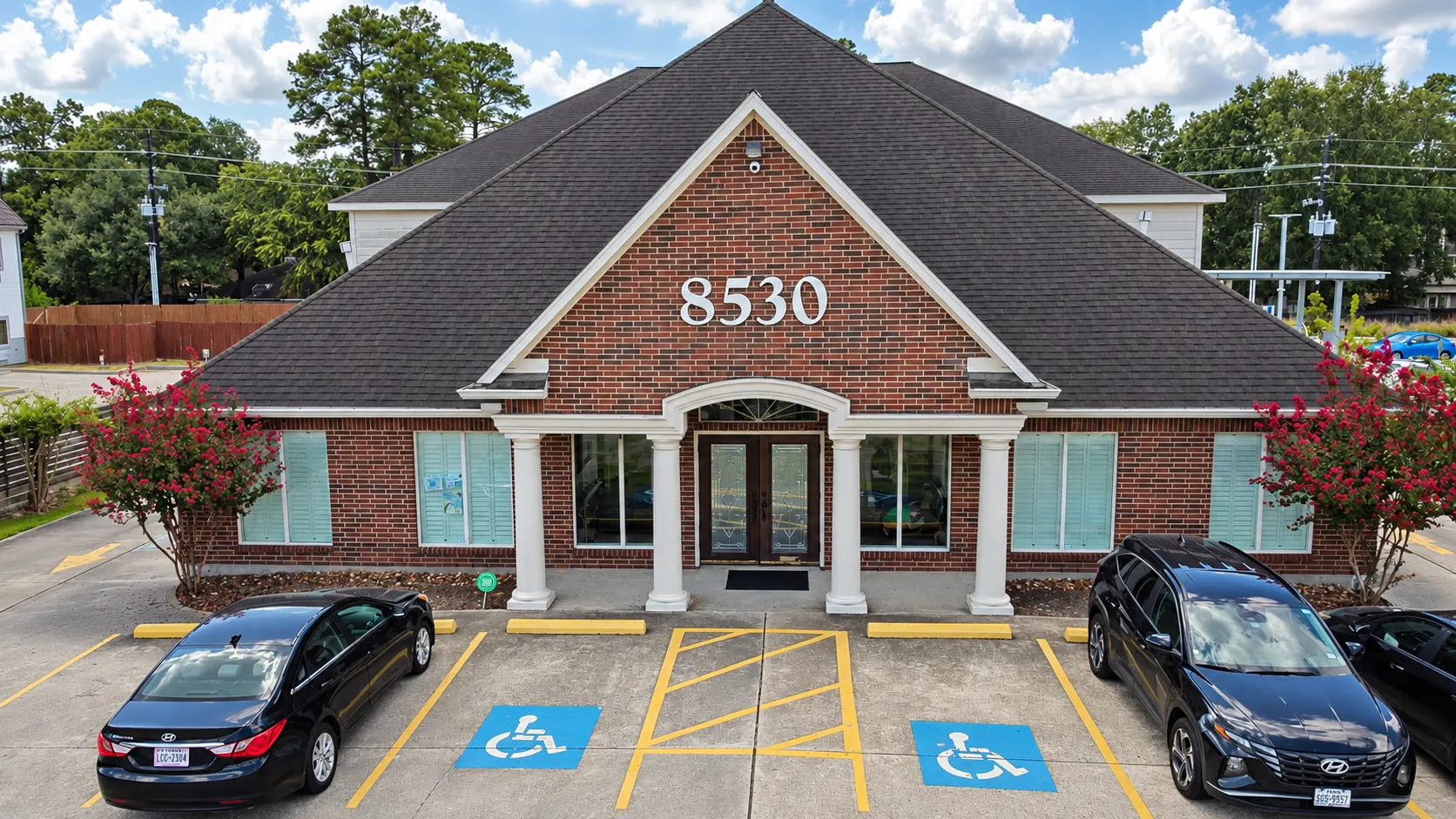 Front exterior of Atascocita Office brick building with 8530 address, white columns, and accessible parking.