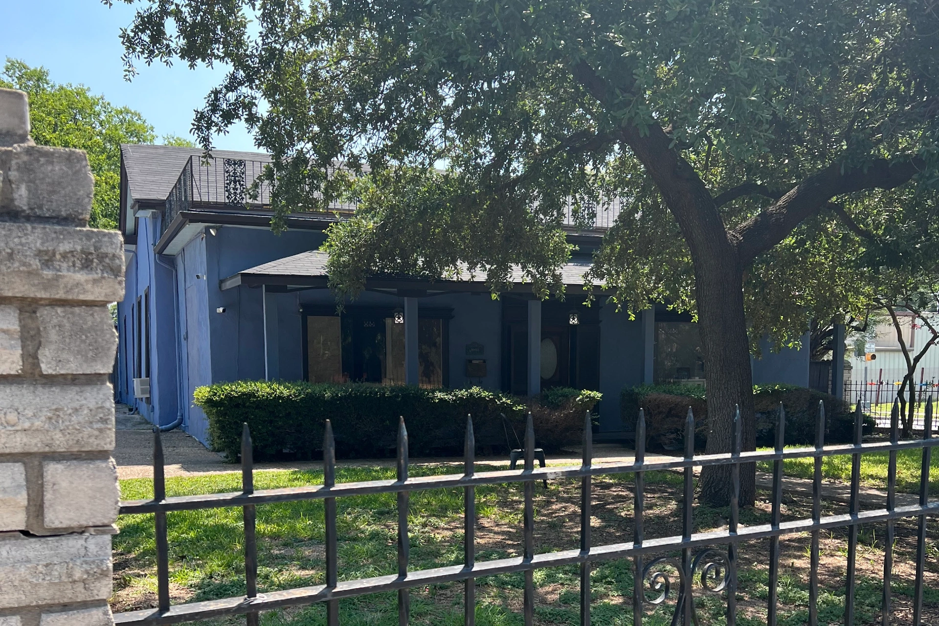 Front view of San Antonio II office building with trees and fenced yard