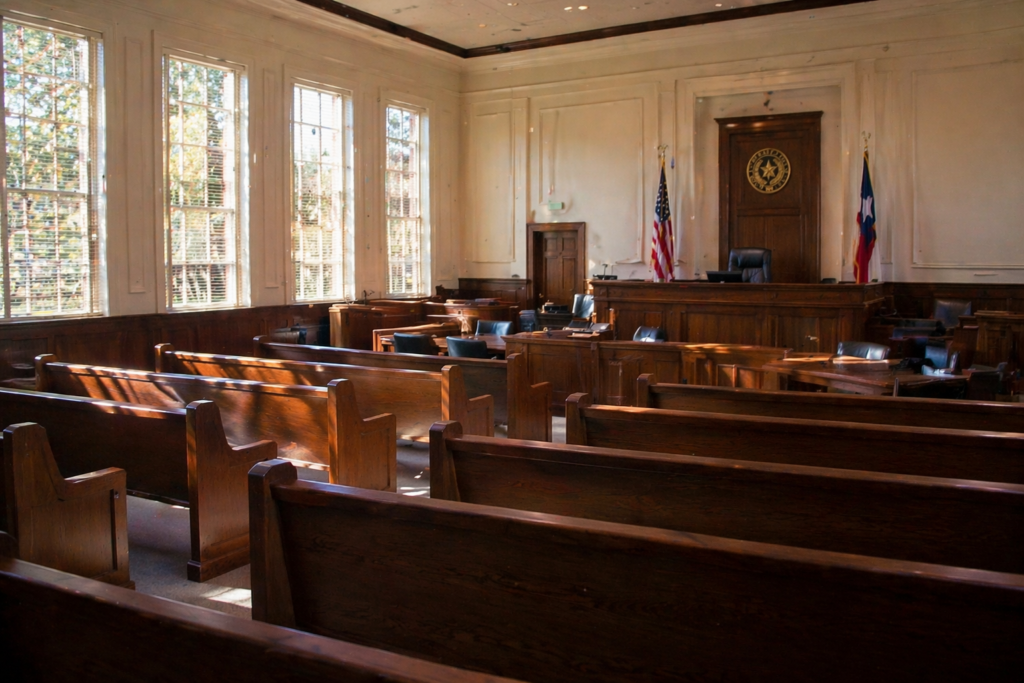 The image depicts a quiet courtroom interior bathed in natural light, featuring empty benches and neutral tones, creating a serene atmosphere. This setting is often associated with serious matters such as child protective services and investigations into child abuse and neglect in Texas.