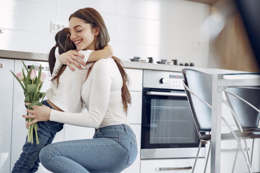 woman hugging her child while holding flowers