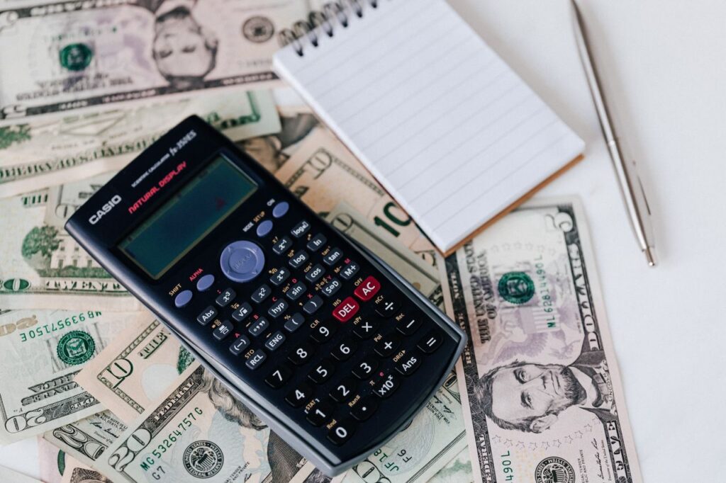 calculator, cash, and notebook on desk