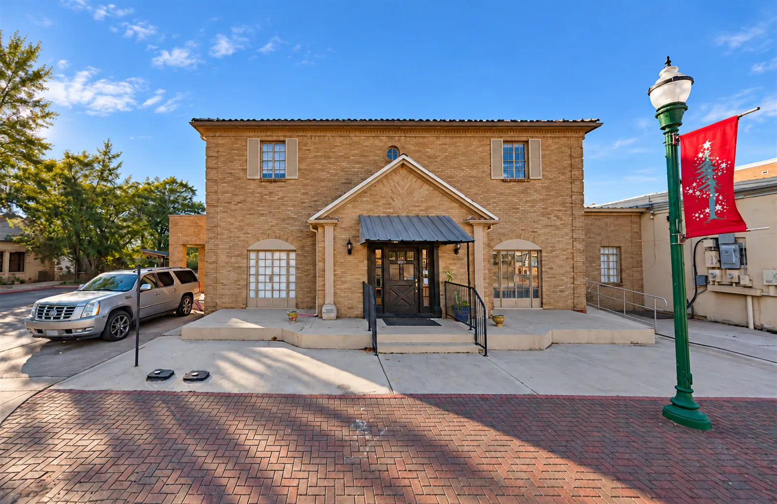Exterior of the Conroe Office brick building with main entrance, sidewalk, and historic streetlamp.
