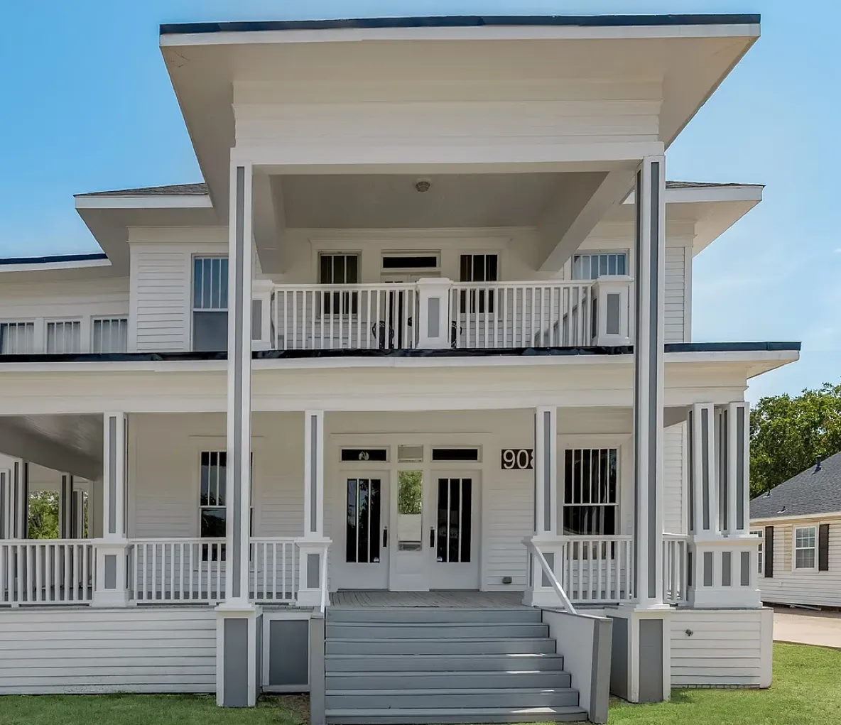 Front exterior of the Rockwall Law Office featuring a two-story white building with covered porches and stairs.